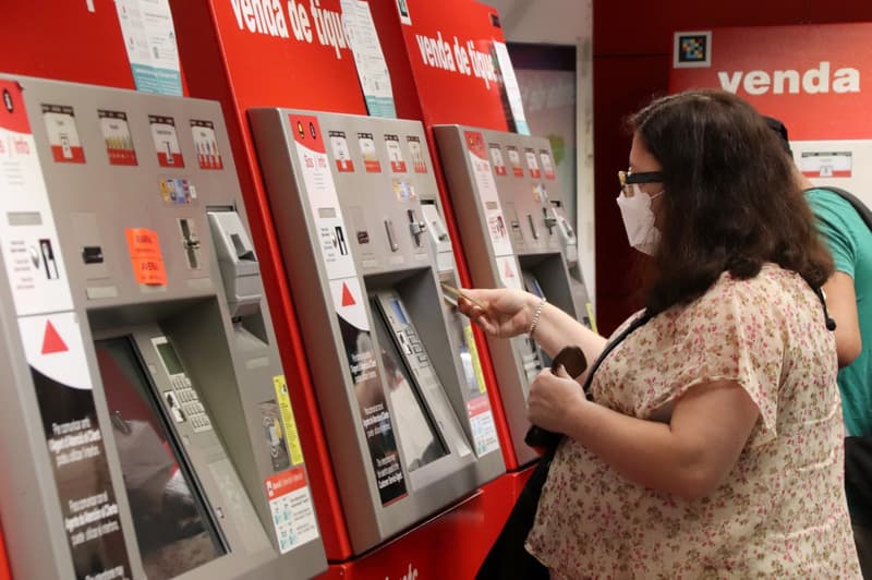 Una dona compra un bitllet de transport públic en una màquina
