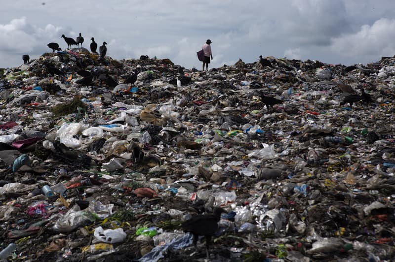 Una mujer anda|camina sobre toneladas de basura plástica en uno de los vertederos a cielo abierto que hay en Guatemala, uno de los países con peor gestión de residuos sólidos en todo el planeta. 23 de mayo del 2022, Guatemala.