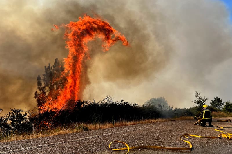 Efectius de bombers que treballen a l'extinció d'un incendi forestal a la carretera N120. El 31 de juliol de 2022, a A Cañiza (Pontevedra) | EFE/ Sxenick