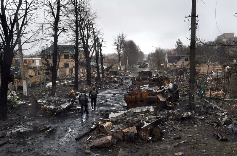 Soldados ucranianos inspeccionan los escombros de tanques rusos destruidos en una carretera en el óblast de Kiev. A medida que las tropas rusas se retiran de las áreas al norte de la capital ucraniana, los funcionarios ucranianos califican las numerosas bajas civiles encontradas en la ciudad de Bucha como un crimen de guerra deliberado, lo que genera la condena internacional. 3 d'abril de 2022, Bucha (Ucrania)