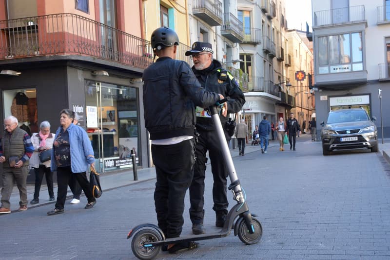 Un agente de la Policía Municipal de Olot con un conductor de patinete eléctrico