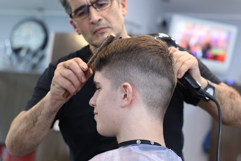Un barber tallant els cabell a un client