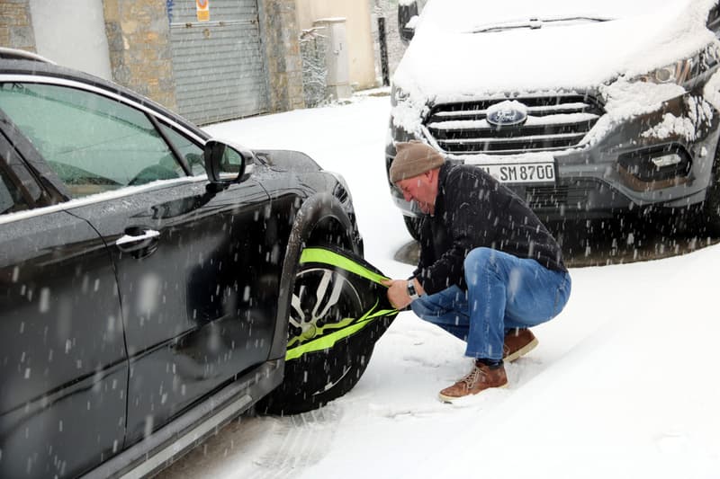 Un hombre pone las cadenas de nieve a su coche en Esterri d'Àneu