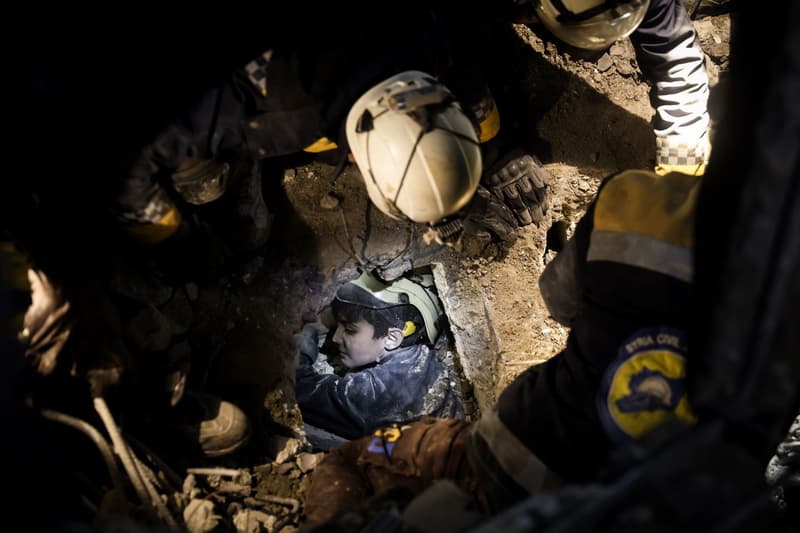 Los servicios de emergencia ayudan a un chico a salir de los escombros de un edificio hundido por los terremotos en Siria
