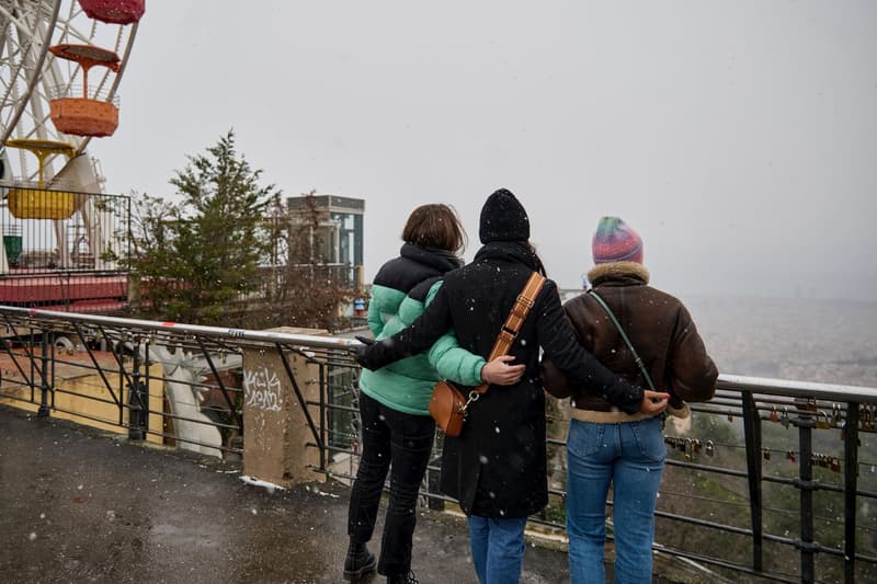 Tres persones al mirador de la muntanya del Tibidabo mentre neva a Barcelona