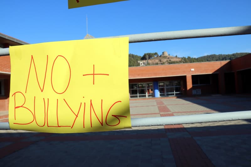 Un cartell que posa 'No més bullying'. Al fons, l'entrada de l'Institut Llobregat.