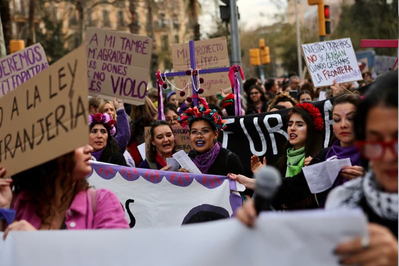 Dones subjectant cartells amb lemes feministes pel 8-M a Barcelona