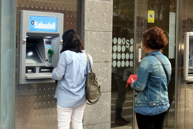 Clientes del Banco Sabadell retirando dinero del cajero