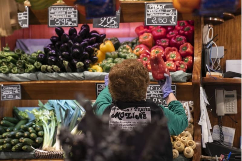 Una mujer trabajando en un puesto de frutas y verduras del mercado