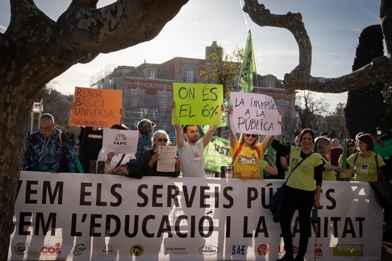 Diverses persones amb cartells i una pancarta durant una concentració a favor de la Renda Bàsica Universal, a 10 de març de 2023, a Barcelona