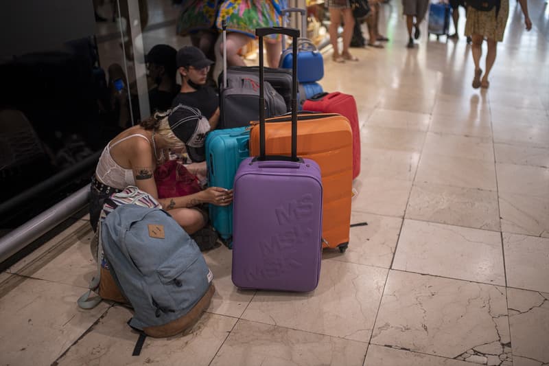 Arxiu: Diverses persones assegudes a terra amb maletes a l'estació d'Ave Barcelona-Sants
