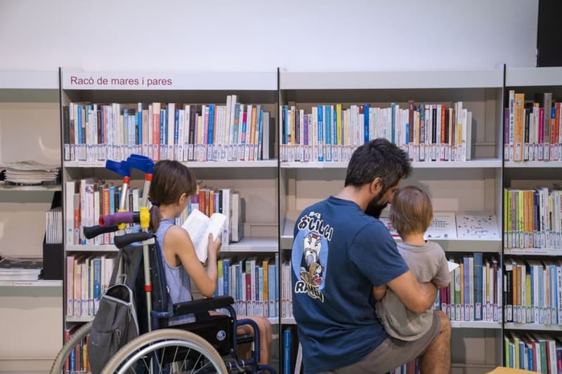 Una familia con un niño y una niña en silla de ruedas consultan libros