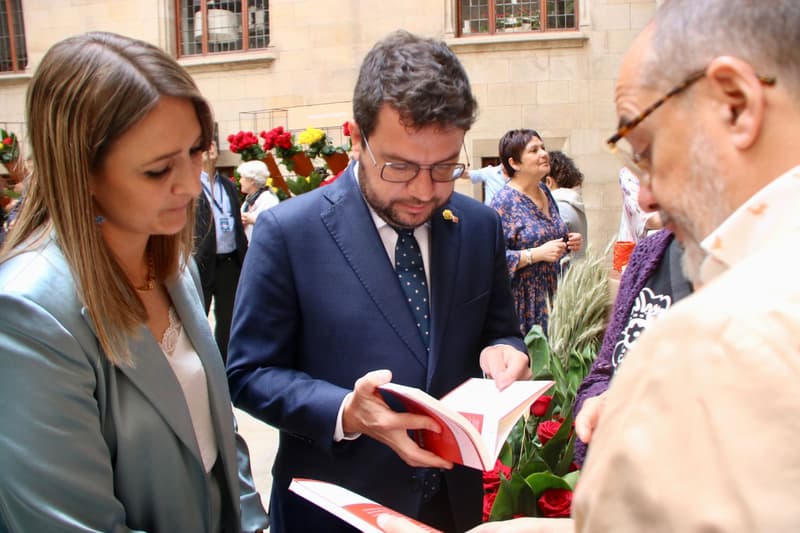 Pere Aragonès mira un libro para|por Sant Jordi en el Palau de la Generalitat