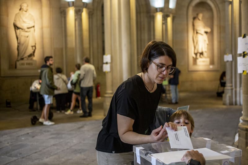 Una mujer votando con su hijo en la Universidad de Barcelona