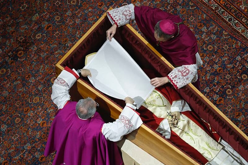 Dos sacerdotes preparan el féretro del papa emérito Benedicto XVI para trasladarlo a la cripta vaticana