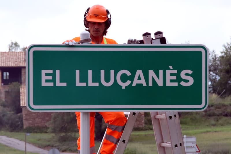 Els operaris destapen el cartell que indica l'entrada a la comarca del Lluçanès pel municipi d'Olost