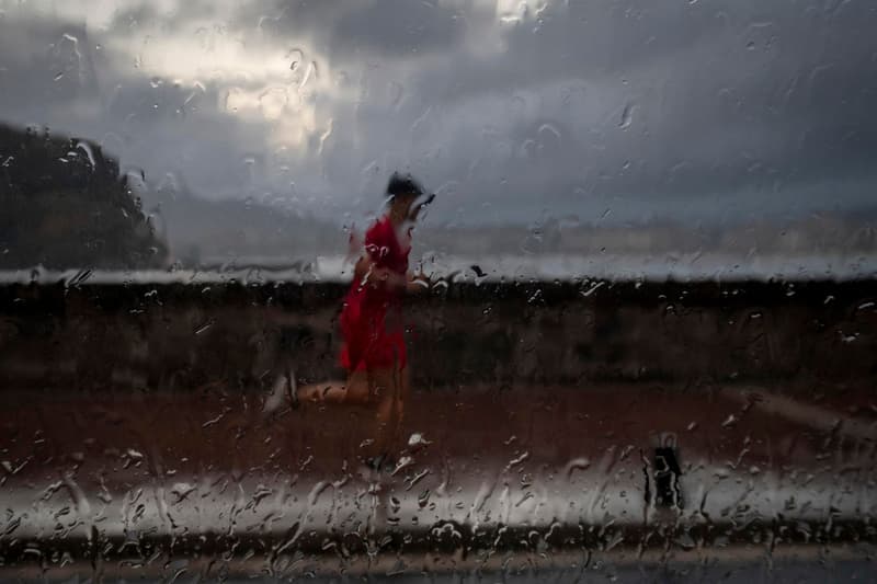 Un home fent esport sota la pluja, vist a través d'una finestra