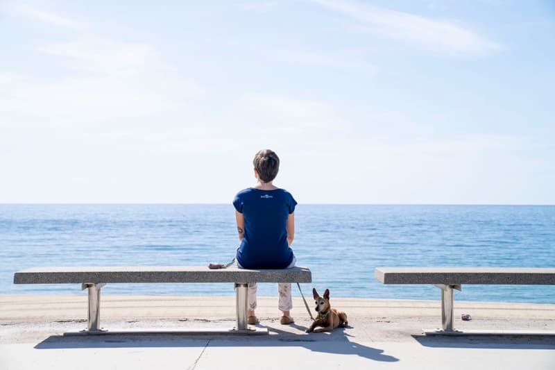 Mujer con un perro sentada en un banco del paseo Marítimo del Bogatell