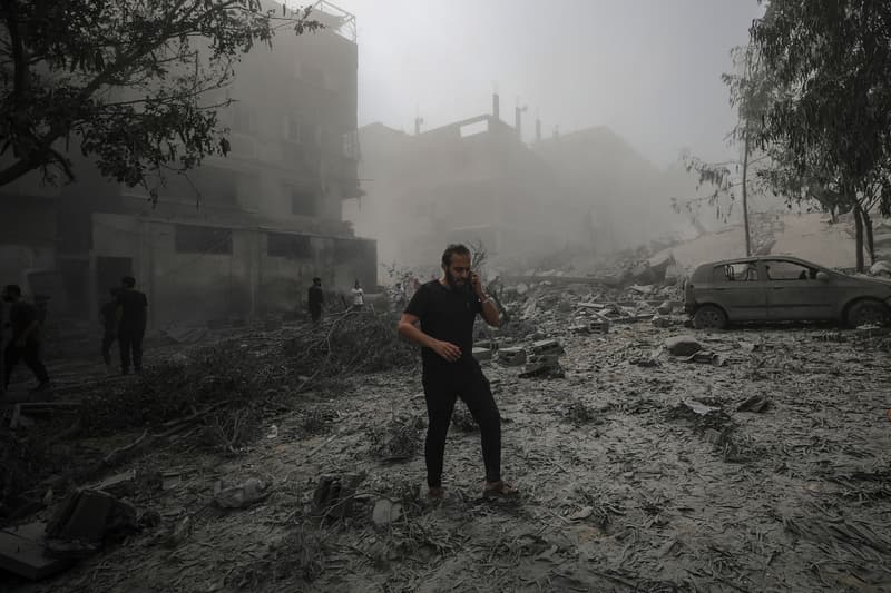Un palestí camina amb el telèfon mòbil per una zona destruïda després dels atacs aeris israelians a la ciutat de Gaza.
