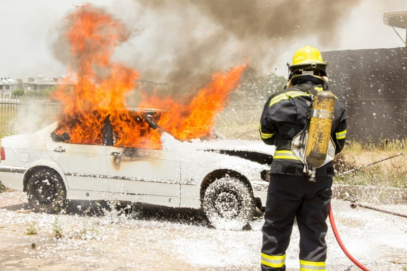 Un bombero apagando un coche que se ha incendiado